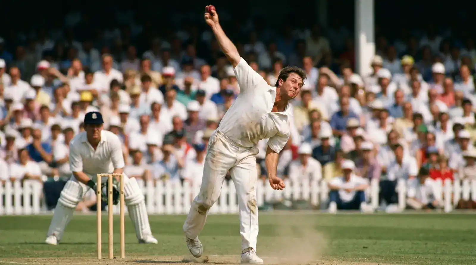 Fast bowler in delivery stride at a Test match with the wicket-keeper crouched behind the stumps