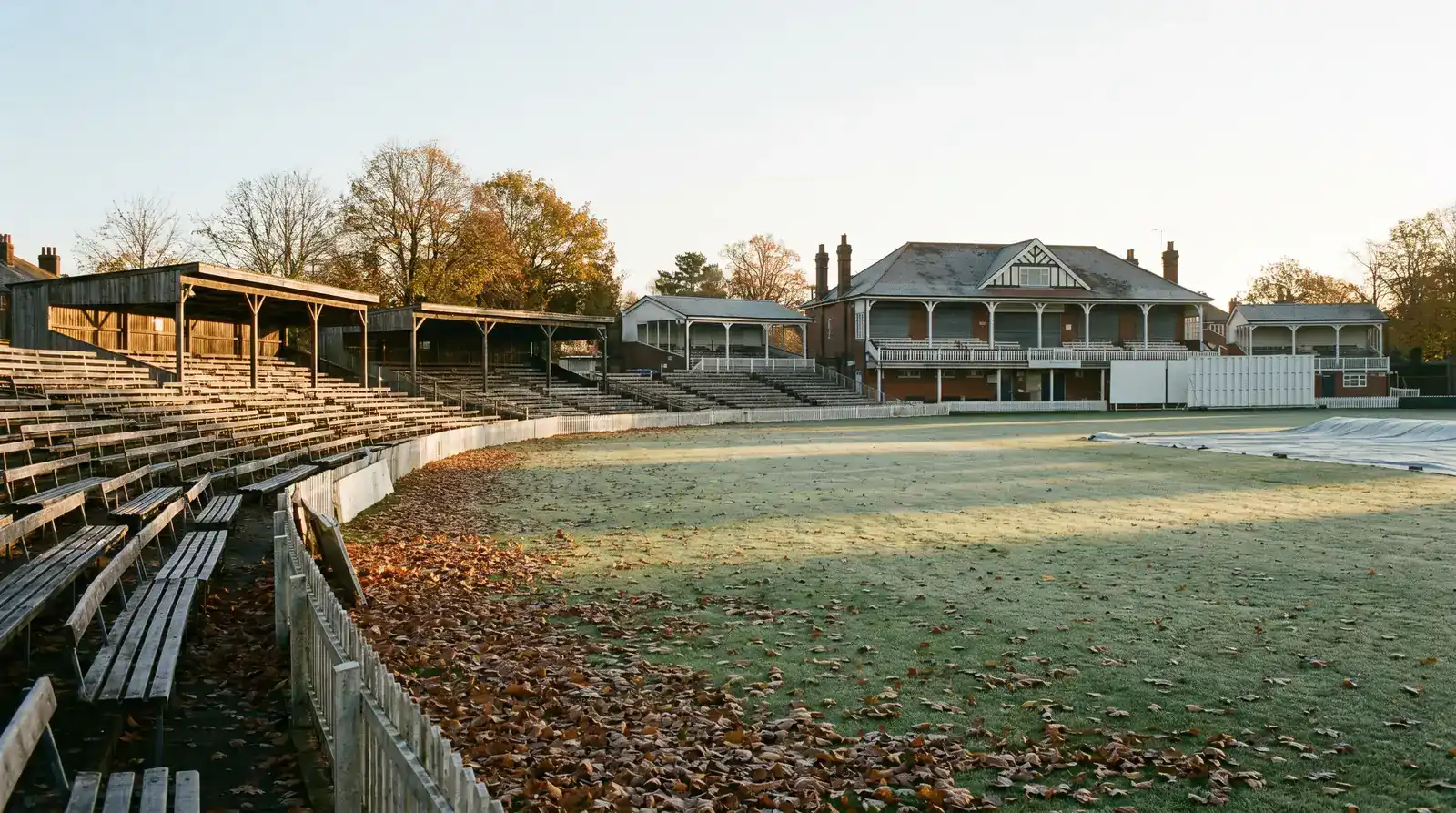Empty English county cricket ground in late autumn with covers on the square and bare stands