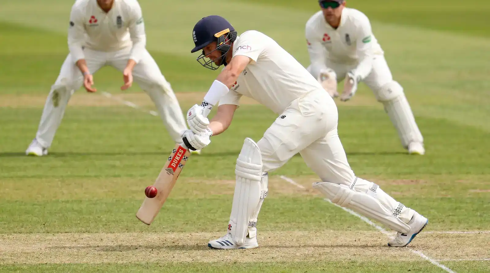 Test cricket batter playing a defensive forward shot to a good-length delivery during a tight maiden over