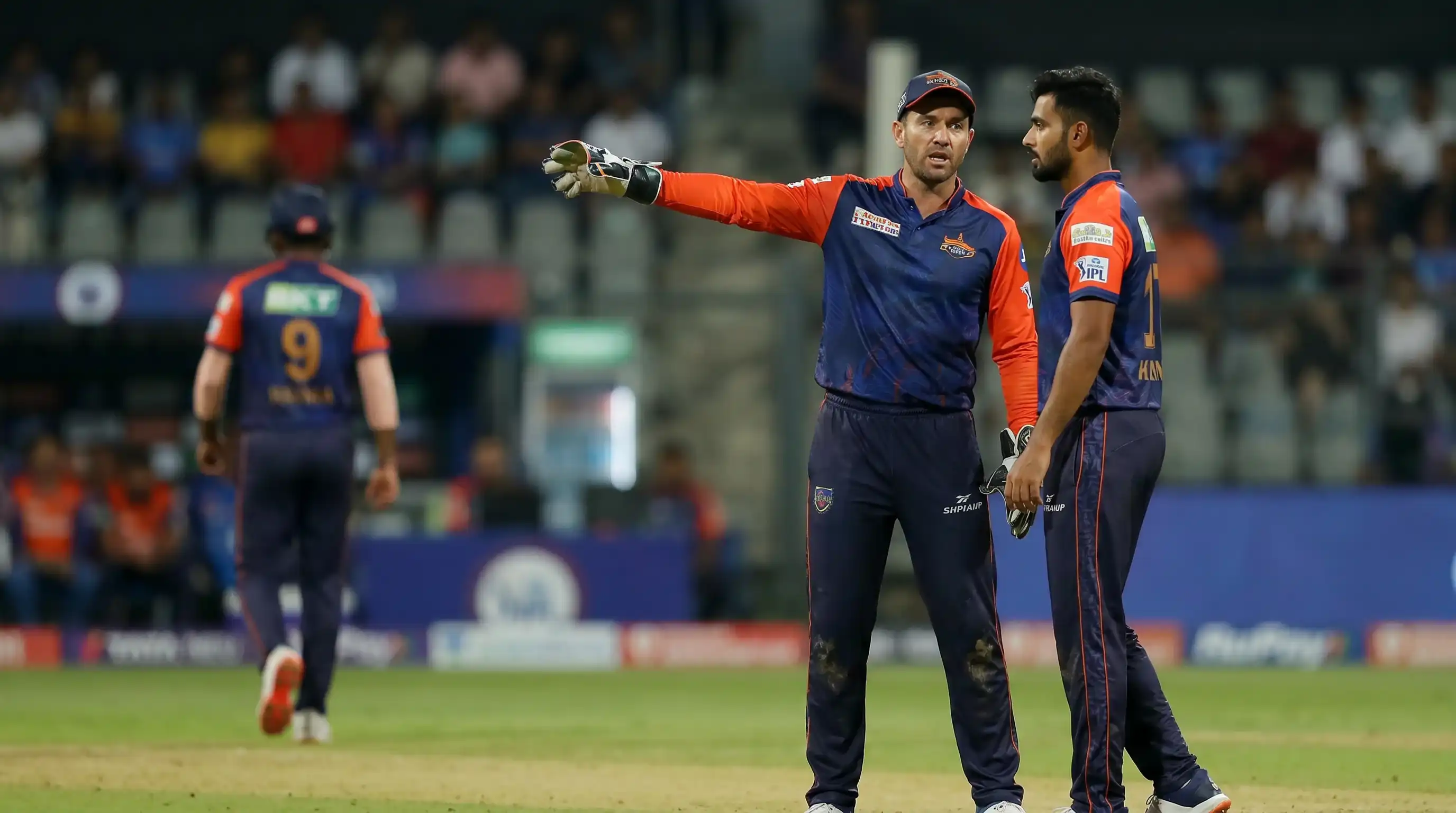 Cricket captain pointing out a fielding position to a teammate during the powerplay setting