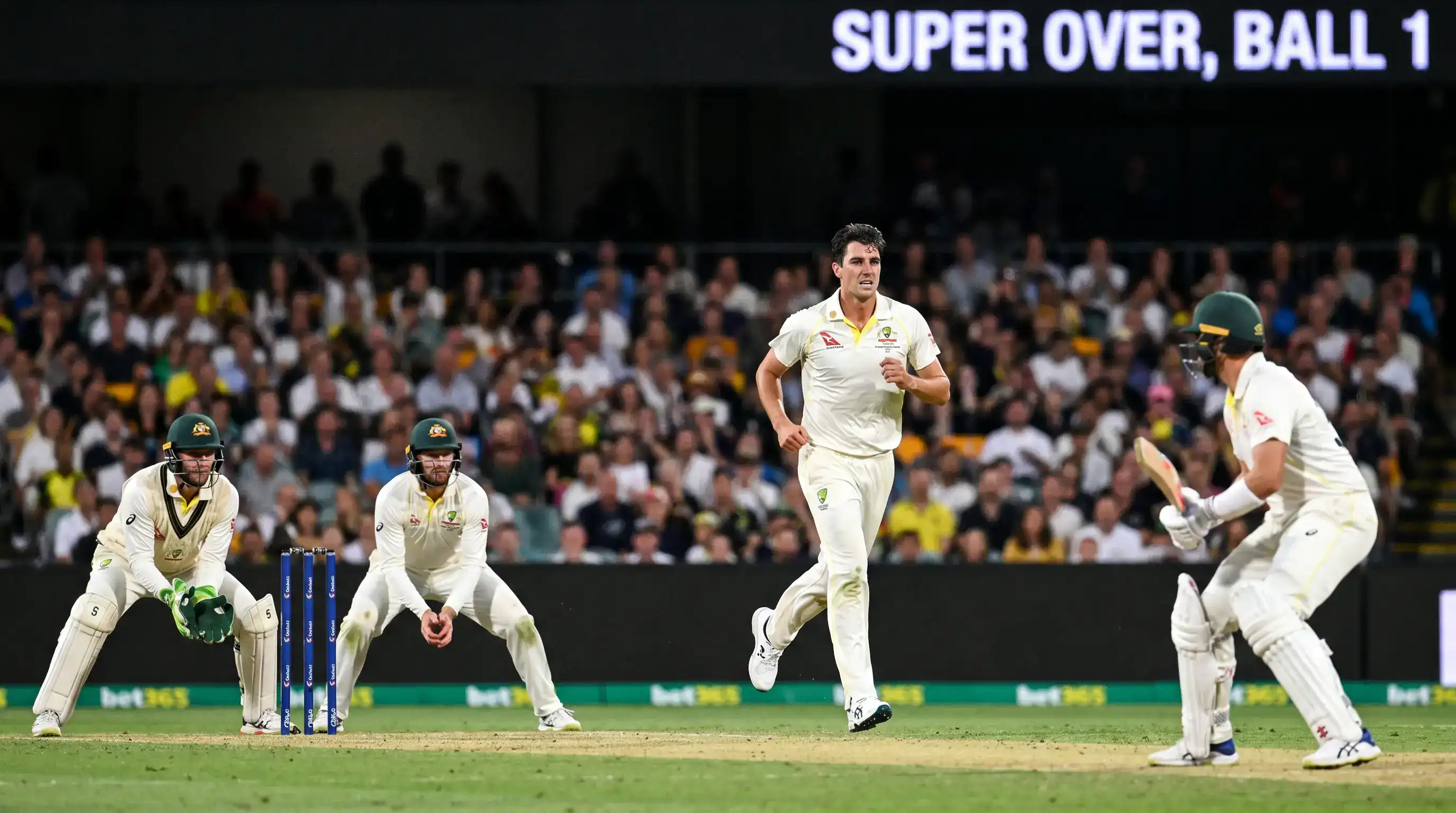 Cricket batter facing the first delivery of a super over with the bowler running in and fielders crowding the catching positions