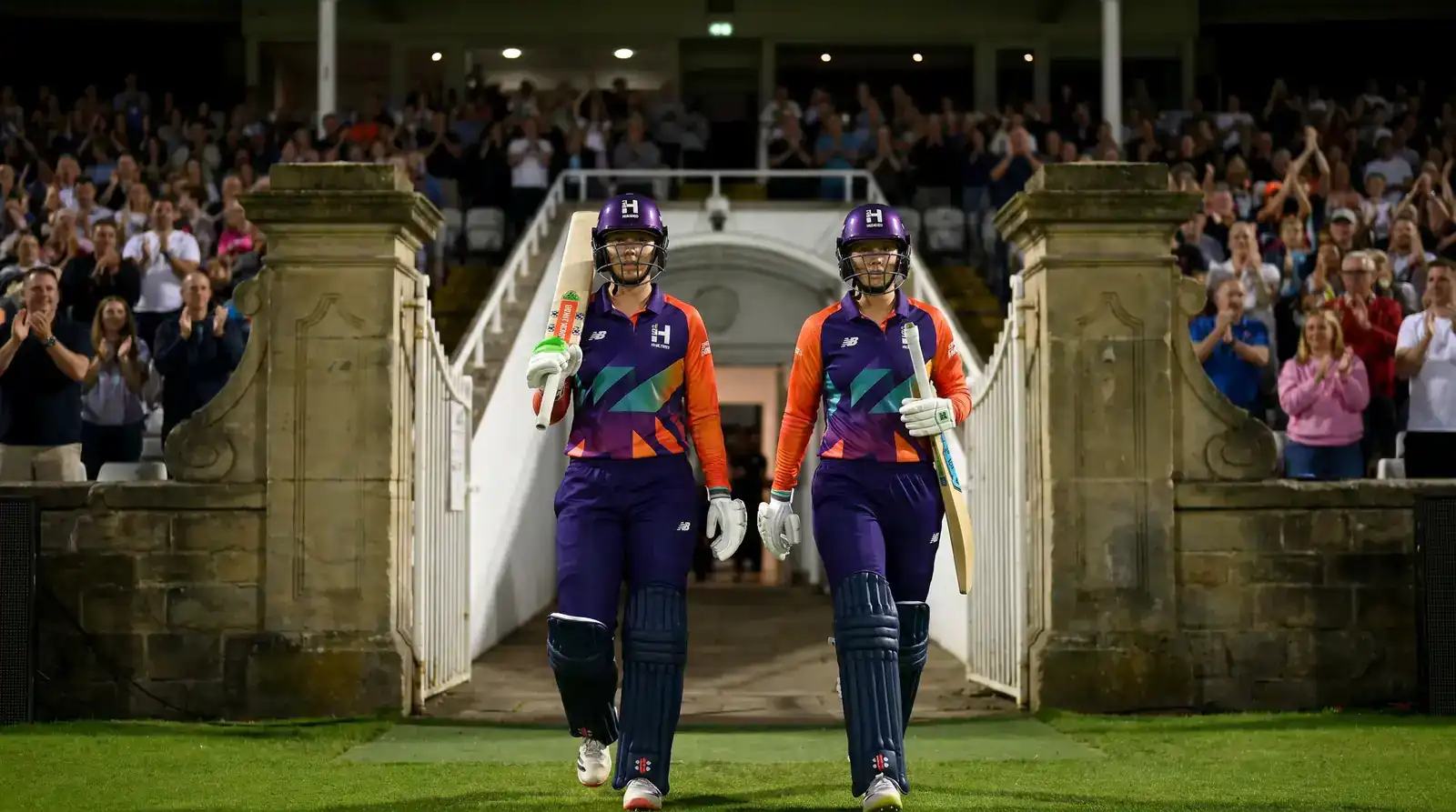 Women's Hundred batters walking out of the pavilion to start an innings under floodlights at an English ground